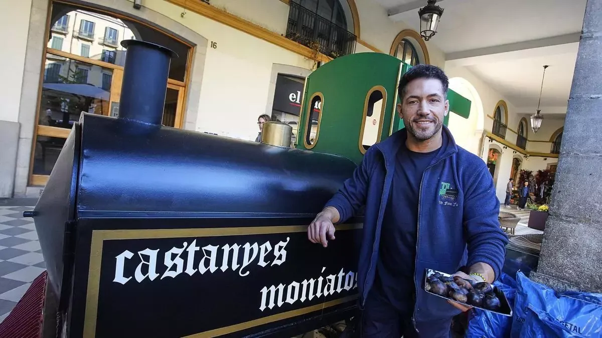 L'Iván Grima recolzat al trenet amb una safata de castanyes, sota les voltes